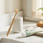 Soft-bristled toothbrush and a tube of toothpaste on a bright bathroom counter