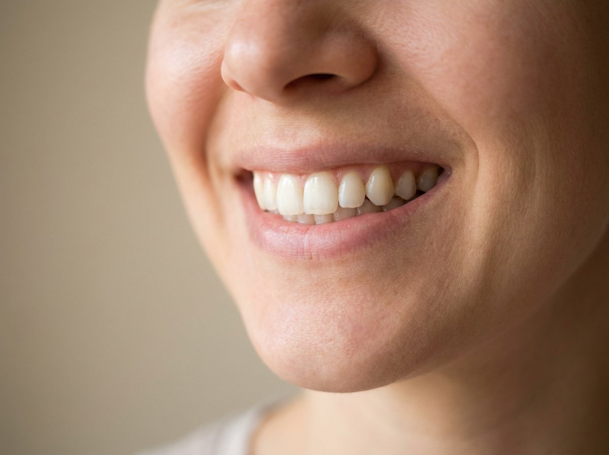 Close-up of an adult smile with naturally bright teeth against a neutral background