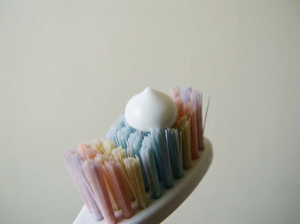 A single pea-sized dot of white toothpaste on the bristles of a small child's toothbrush