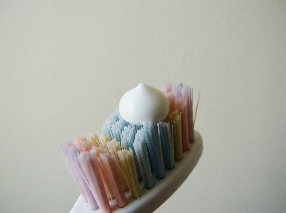 A single pea-sized dot of white toothpaste on the bristles of a small child's toothbrush