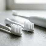 Sonicare replacement heads lined up beside an electric toothbrush handle on a bathroom counter